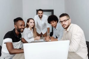 View of team from behind open laptop in conference room, interacting with screen