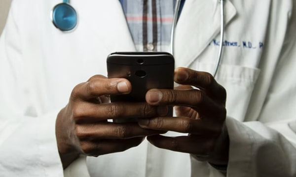 Close up view of male doctor from the neck down holding and operating a smartphone in hands