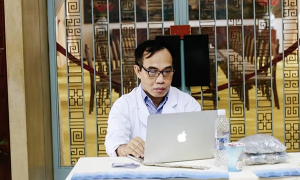 View of male doctor working on laptop, sitting at a covered table in satellite clinic environment in conference hall