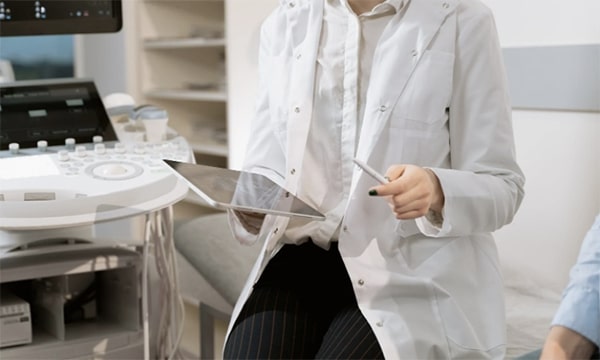 Business casual woman seated and working on laptop at a table with mouse and iPhone at table in a computer lab